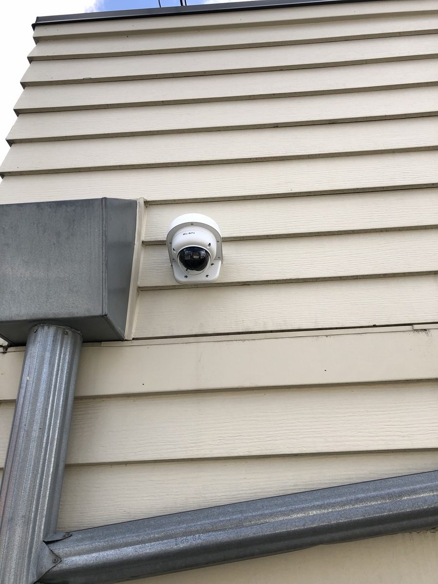Dome security camera mounted on the exterior siding of a building