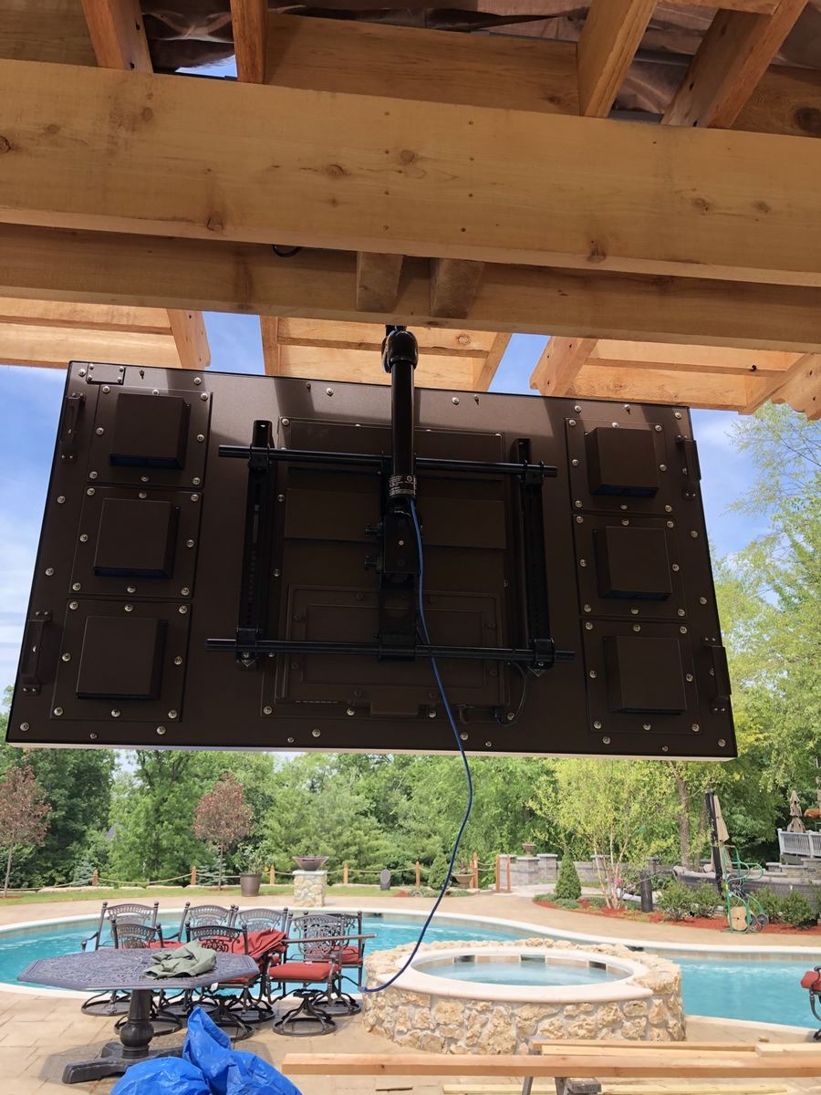 Before: back of an outdoor TV hanging from its ceiling mount under the pergola, wiring visible