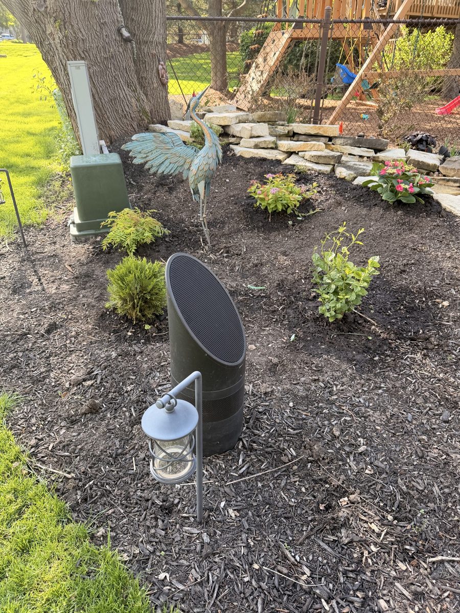 Landscape speaker installed among plants in a garden bed