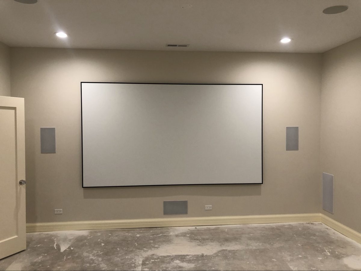 Before: home theater room under construction, bare concrete floor and blank projector screen
