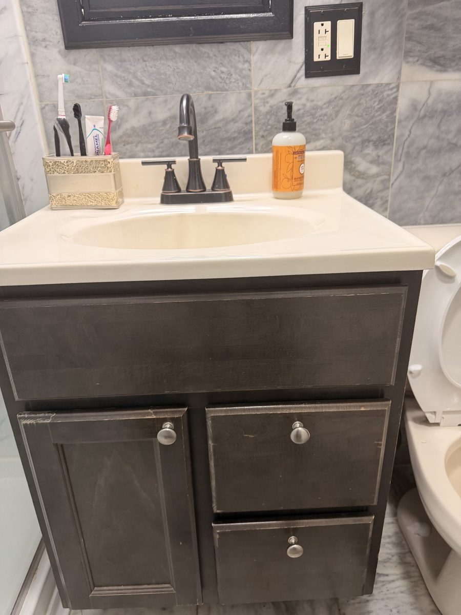 Before: old dark-wood bathroom vanity with a worn top