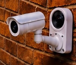 White surveillance cameras mounted on a brick wall